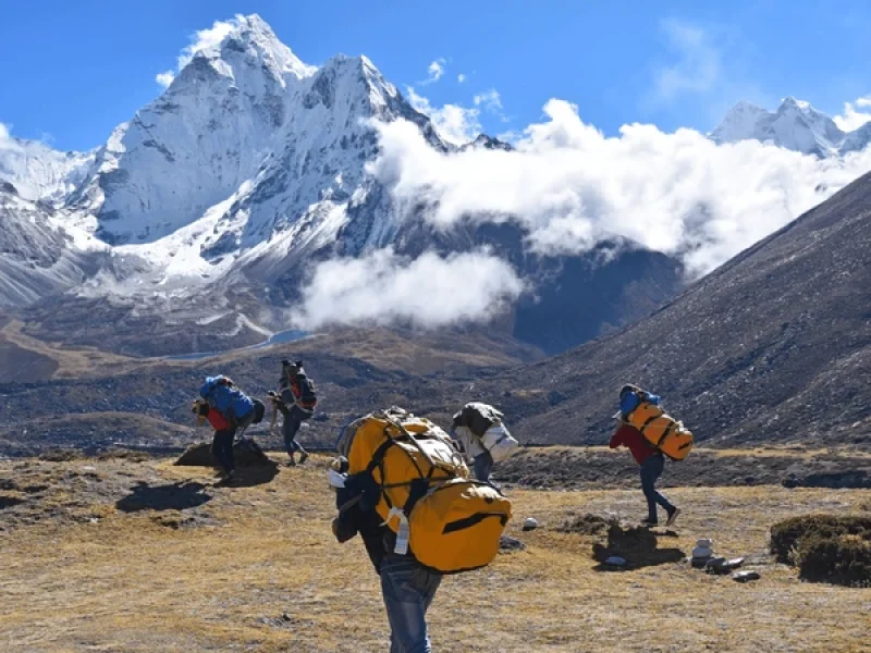 sherpa guides carrying backpacks of trekkers